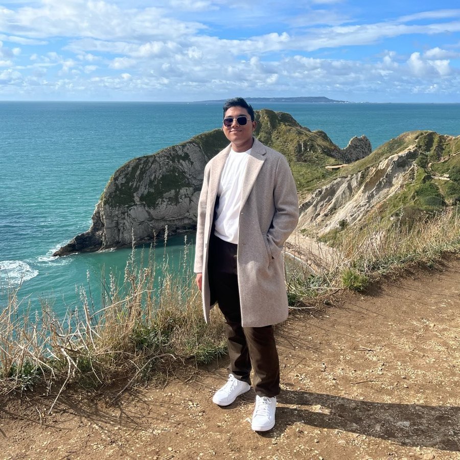 Senaajit standing on a clifftop path above a turquoise bay on the English coast